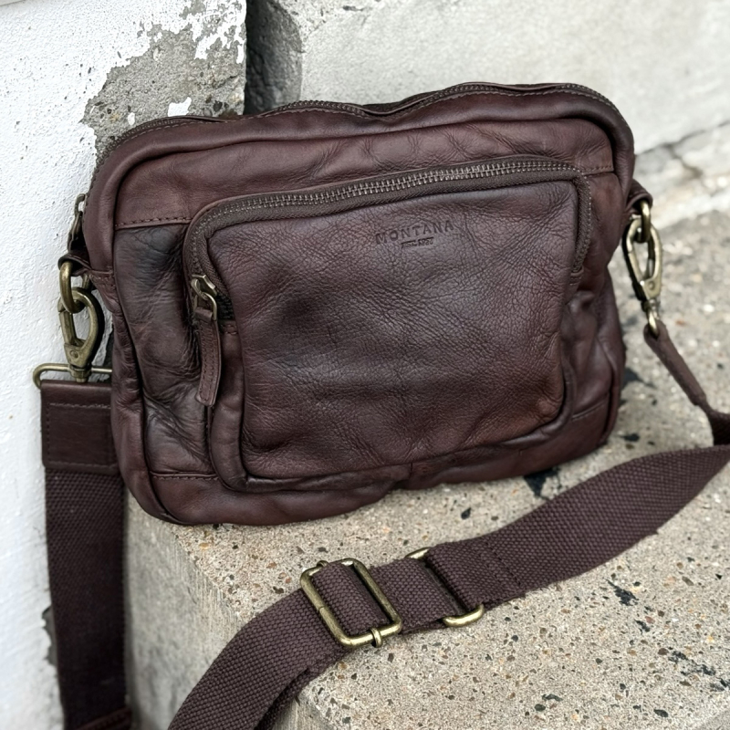 Dayton crossbody taske i brun bøffelskind - stående på sten vist forfra