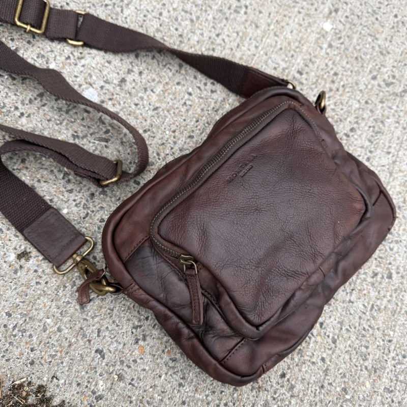 Dayton crossbody taske i brun bøffelskind - liggende fladt på sten